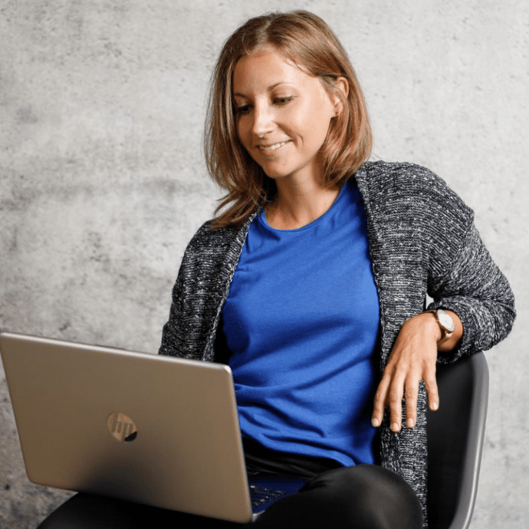 Caucasian woman sitting on a chair looking at a laptop on her lap