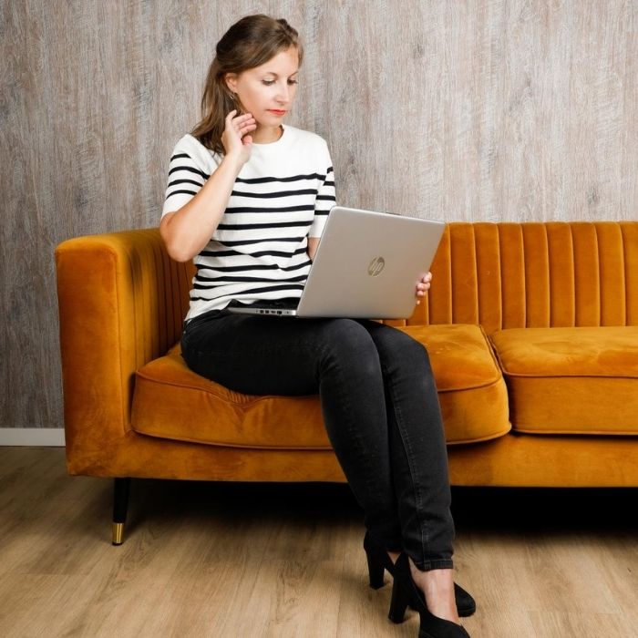 Caucasian woman sitting on a sofa looking at a laptop on her lap